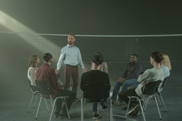 A diverse group participating in a therapy session with a facilitator indoors.